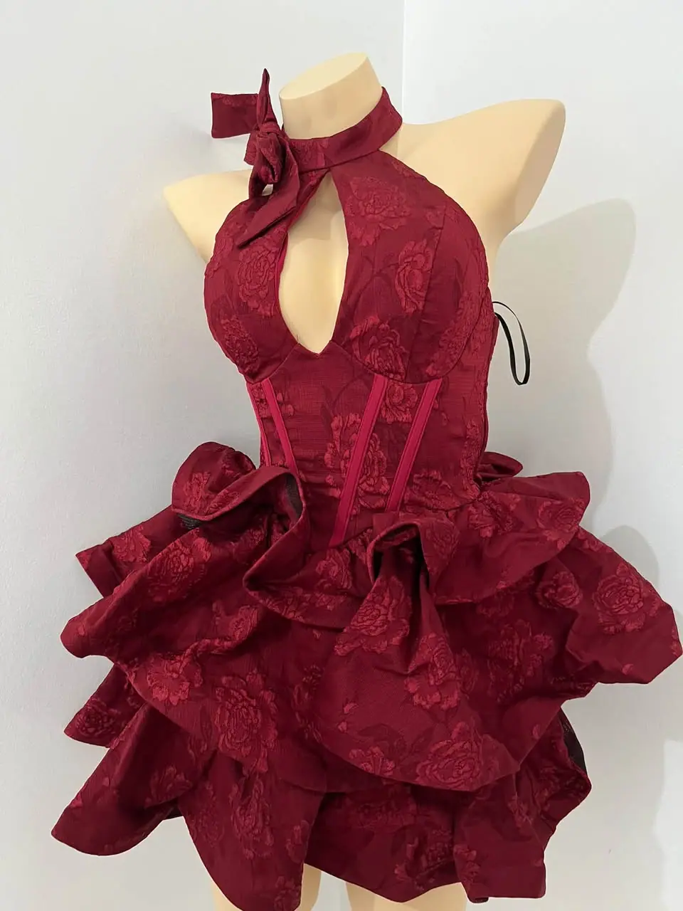Rose’s wine red floral fabric, bow neckline and cascading ruffles from Grathéa’s gown rental collection